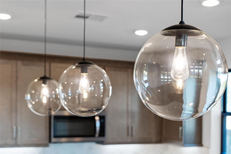 Contemporary pendant lights hang above the island, adding a touch of modern design, complemented by recessed lighting throughout the ceiling for overall illumination. Contemporary pendant lights hang above the island, adding a touch of modern design, complemented by recessed lighting throughout the ceiling for overall illumination.