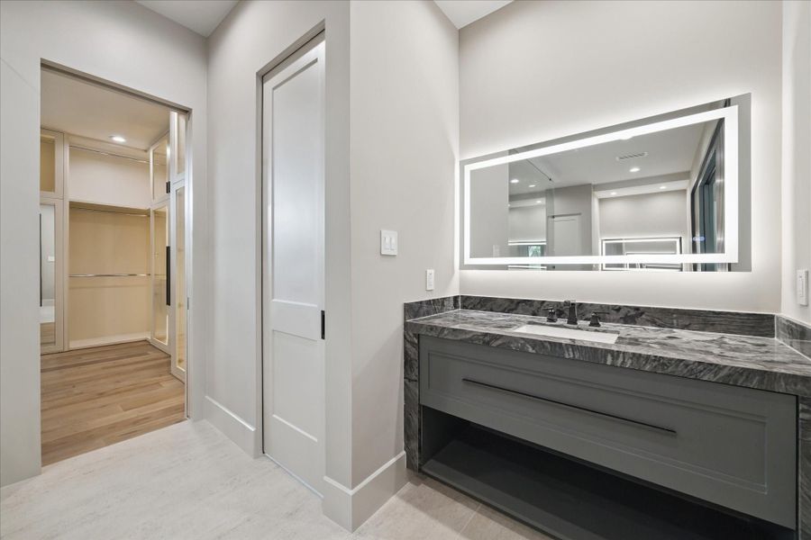 Sleek fixtures, textured wall accents, and abundant natural light enhance the sophisticated ambiance, making this bathroom a true retreat.