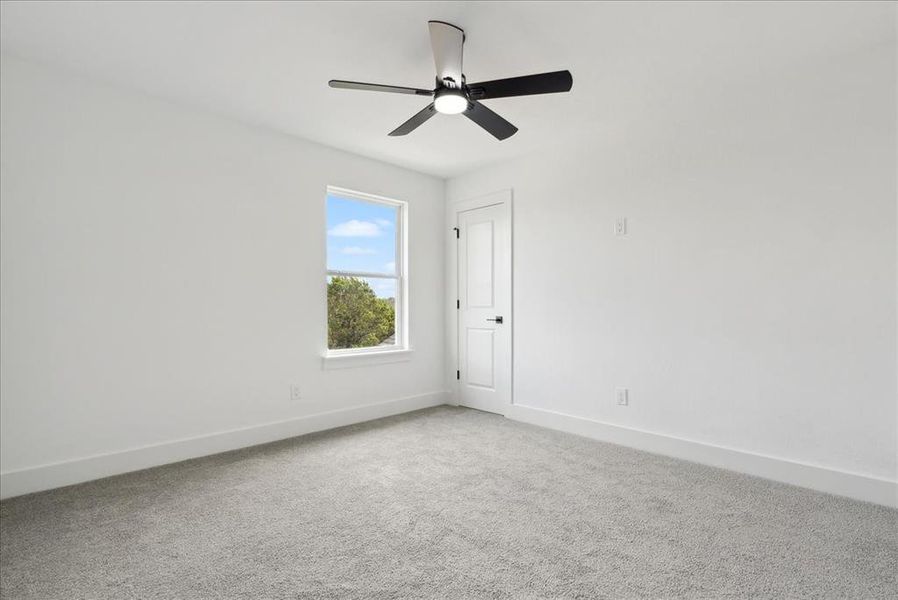 Carpeted empty room featuring ceiling fan