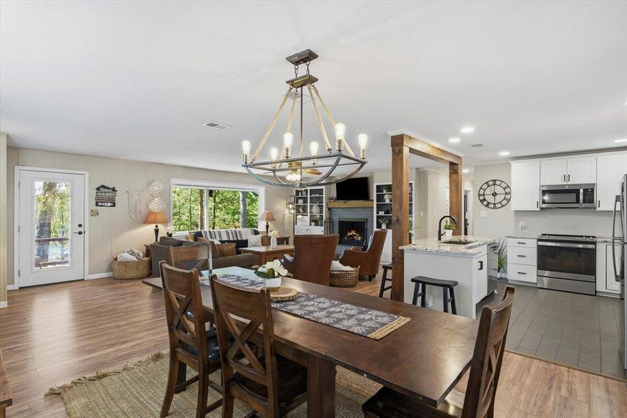 Open-concept interior featuring a kitchen island with seating, stainless steel appliances, white cabinetry, and a fireplace