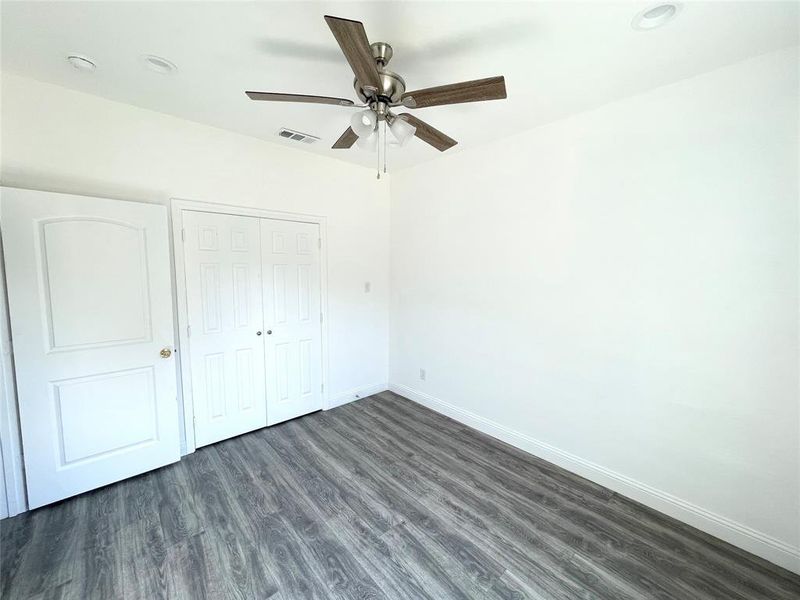 Unfurnished bedroom with ceiling fan, a closet, and dark hardwood / wood-style flooring