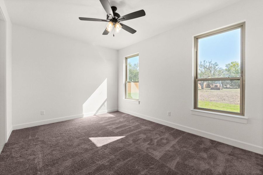 Empty room featuring dark colored carpet and a ceiling fan