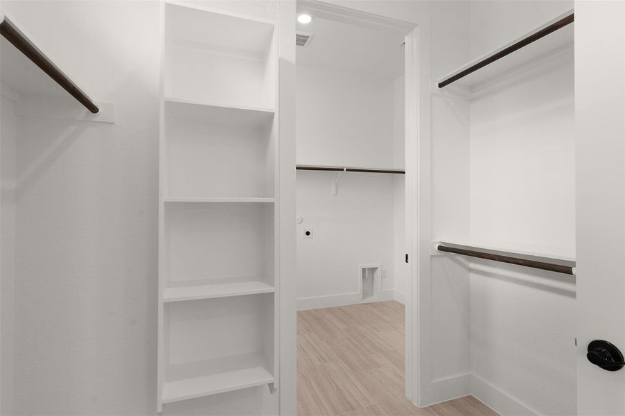Spacious closet with light wood-style flooring Spacious closet with light wood-style flooring