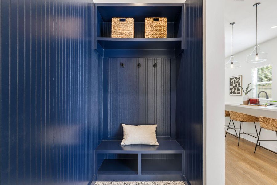 The elegantly designed mudroom with wainscoting, a bench, and cubbies offers practical yet stylish storage solutions. Located at the home's entryway.