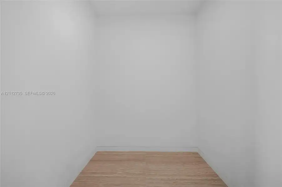 Enclosed space featuring neutral walls and wood-finish flooring