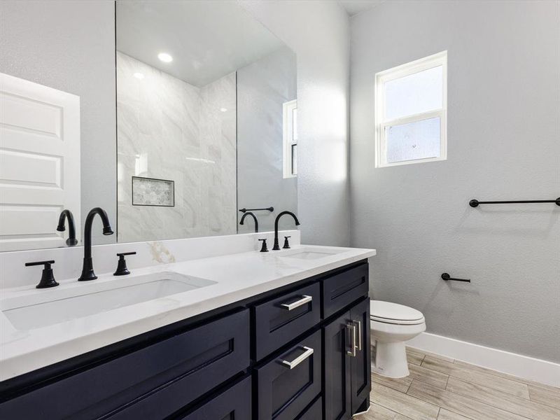 Full bathroom featuring double vanity and wood finish floors Full bathroom featuring double vanity and wood finish floors