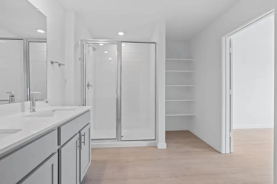 Bathroom featuring a shower stall, double vanity, light wood-style flooring, and recessed lighting Bathroom featuring a shower stall, double vanity, light wood-style flooring, and recessed lighting