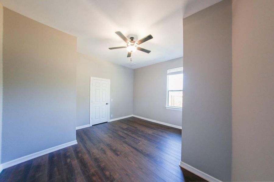 Empty room featuring dark wood-style floors and a ceiling fan Empty room featuring dark wood-style floors and a ceiling fan