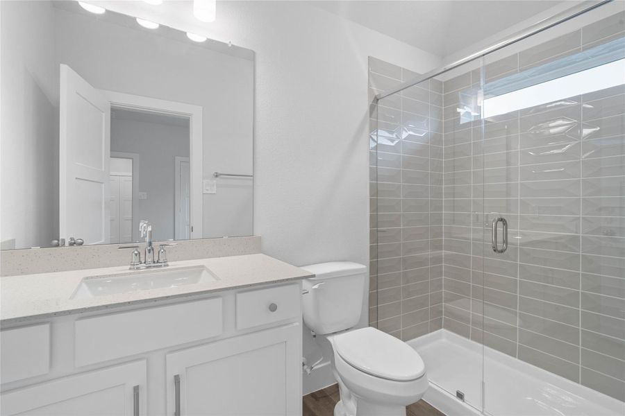 The private en suite bathroom features a modern white vanity and a walk-in shower with sleek tile surround.