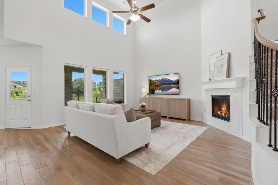 This spacious living room features high ceilings, large windows for natural light, a cozy fireplace, and elegant wood tile flooring. The open layout offers a welcoming atmosphere, perfect for relaxation and entertaining.