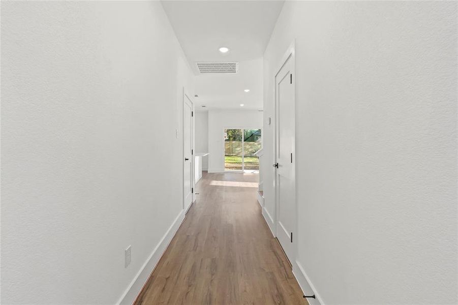 Hall with wood finished floors and recessed lighting