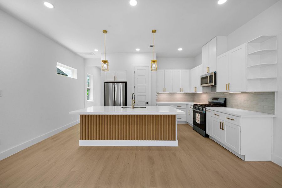 This modern kitchen features sleek white cabinetry, a central island with wood accents, stainless steel appliances, and elegant pendant lighting. The open layout and light wood flooring create a bright and inviting space. This modern kitchen features sleek white cabinetry, a central island with wood accents, stainless steel appliances, and elegant pendant lighting. The open layout and light wood flooring create a bright and inviting space.