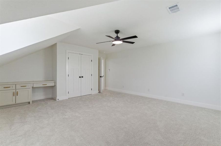 Spacious room featuring light-colored carpet, a ceiling fan with light, and white walls Spacious room featuring light-colored carpet, a ceiling fan with light, and white walls
