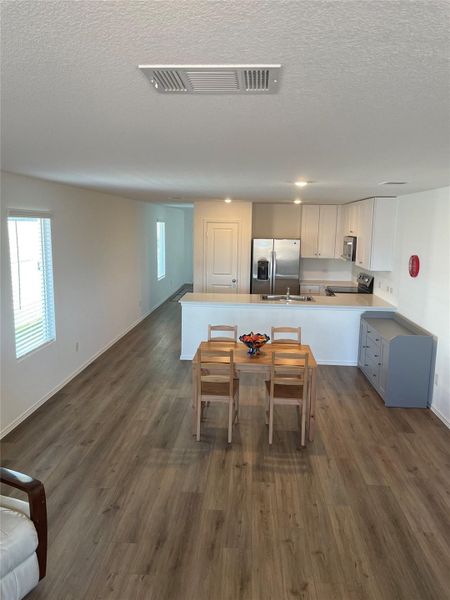 Kitchen with a peninsula, open floor plan, a textured ceiling, stainless steel appliances, and white cabinets
