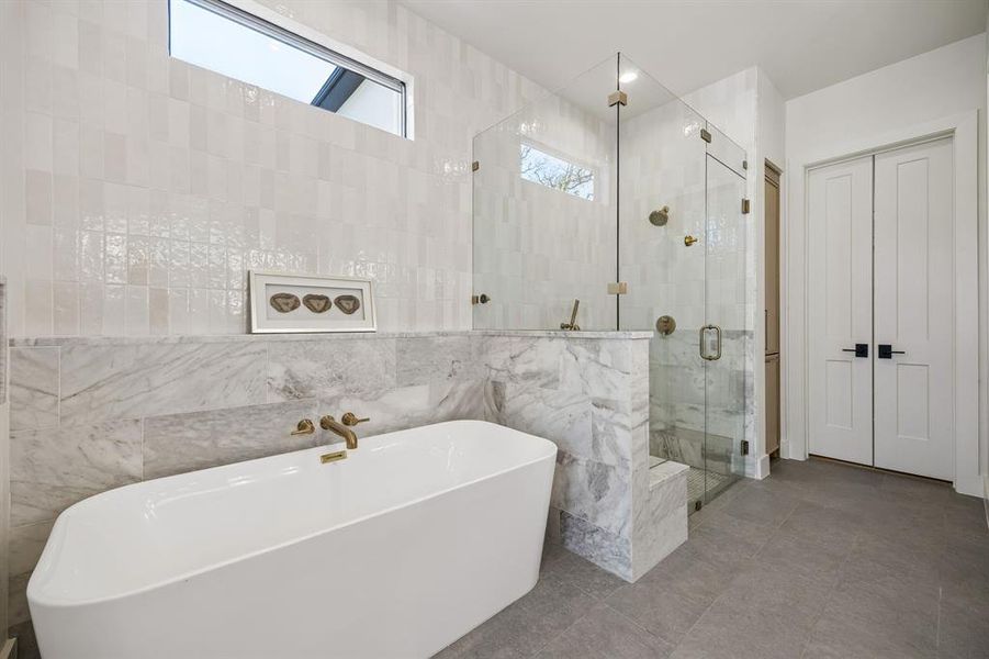 Oversized soaking tub, seamless glass shower surround bathed in natural light.