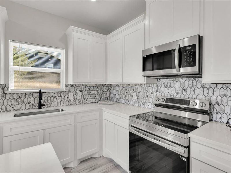 Kitchen featuring white cabinetry, sink, decorative backsplash, appliances with stainless steel finishes, and light wood-type flooring