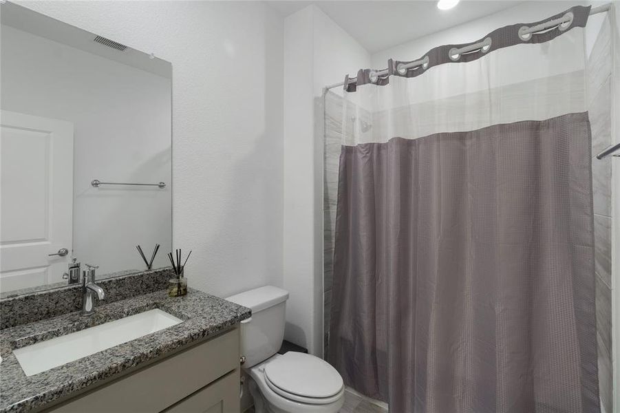 Bathroom featuring a vanity with a granite countertop, integrated rectangular sink, and chrome faucet