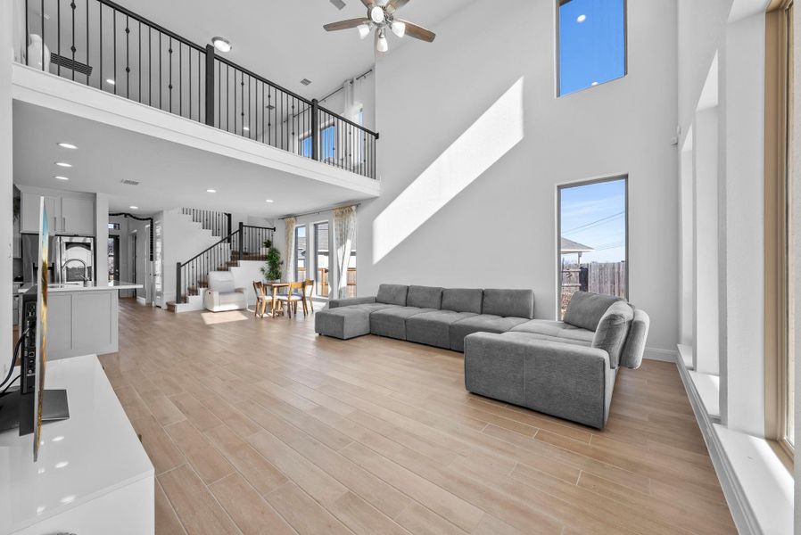 Living area featuring stairway, wood finish floors, ceiling fan, a towering ceiling, and recessed lighting