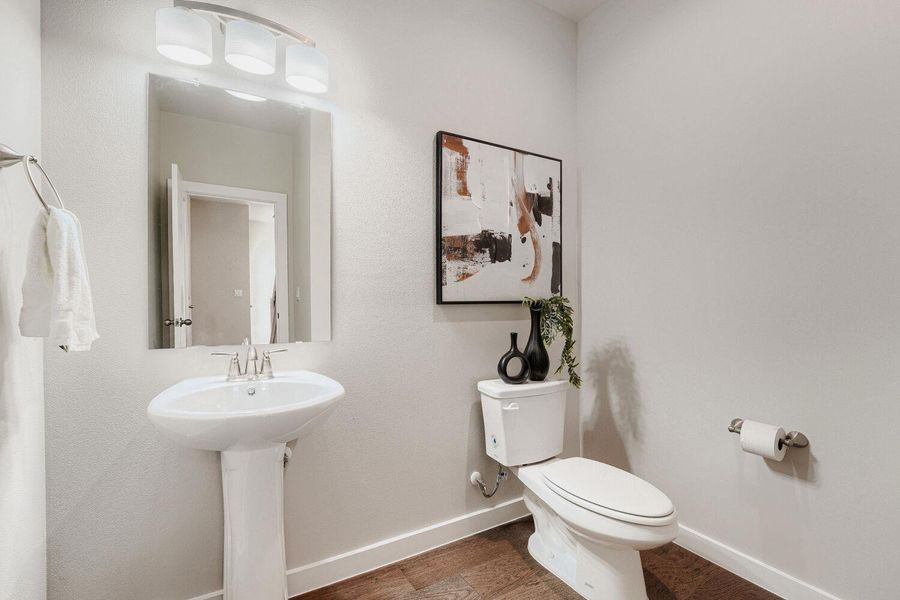 A bright powder room featuring sleek fixtures and warm wood-toned flooring. A bright powder room featuring sleek fixtures and warm wood-toned flooring.