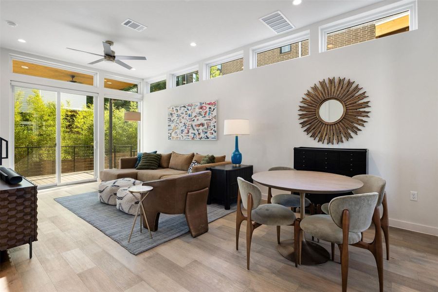 Living room featuring plenty of natural light, ceiling fan, recessed lighting, a high ceiling, and light wood-style floors