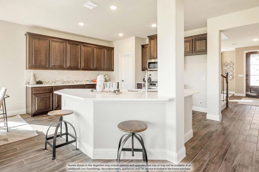Kitchen with dark wood cabinets, white island, two bar stools, and wood-look tile floors Kitchen with dark wood cabinets, white island, two bar stools, and wood-look tile floors