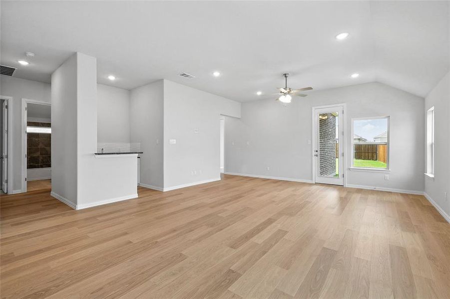 Unfurnished living room with a ceiling fan, light wood-style flooring, vaulted ceiling, and recessed lighting Unfurnished living room with a ceiling fan, light wood-style flooring, vaulted ceiling, and recessed lighting