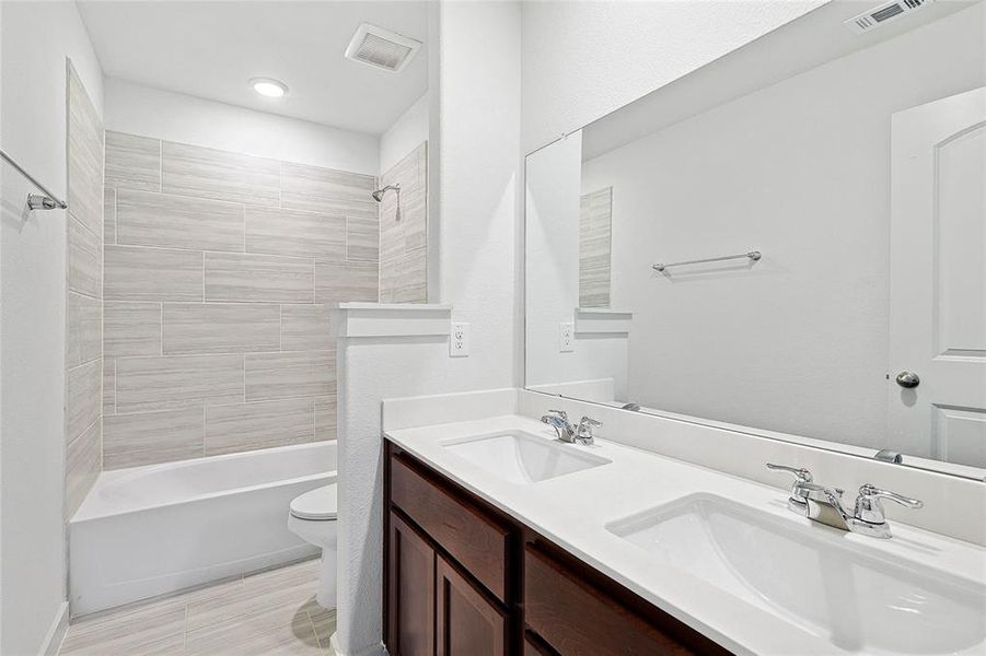 Full bathroom featuring tiled shower / bath, vanity, and toilet