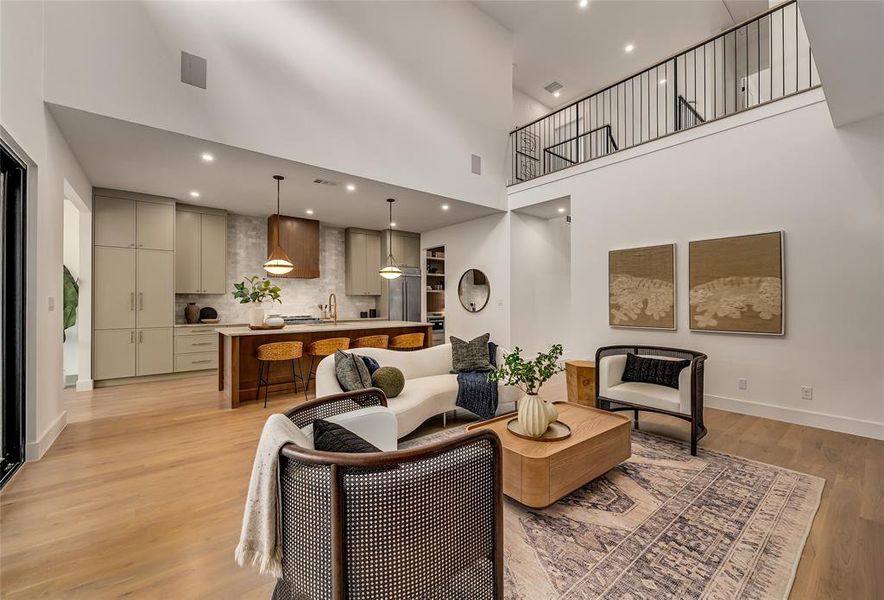 Living area featuring a high ceiling, light wood-style floors, and recessed lighting Living area featuring a high ceiling, light wood-style floors, and recessed lighting