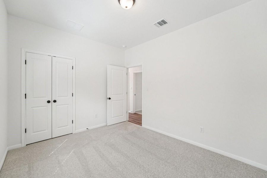 A well-lit room with fresh carpeting and white bi-fold closet doors offers a welcoming, clean aesthetic. A well-lit room with fresh carpeting and white bi-fold closet doors offers a welcoming, clean aesthetic.