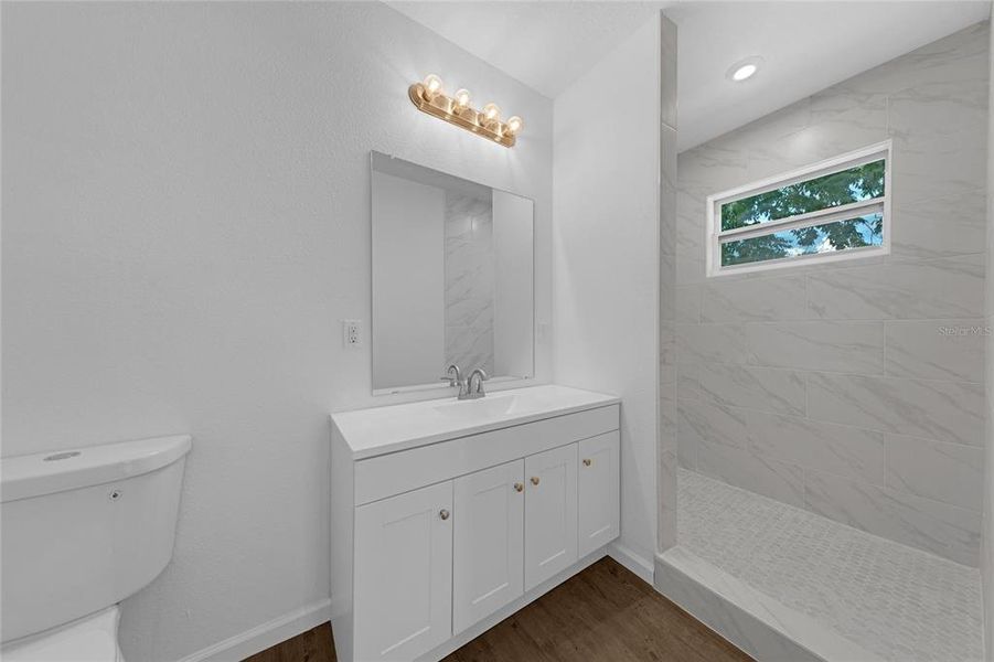 Primary bathroom with large walk-in shower * tile floor and walls in the shower with transom window for nice lighting