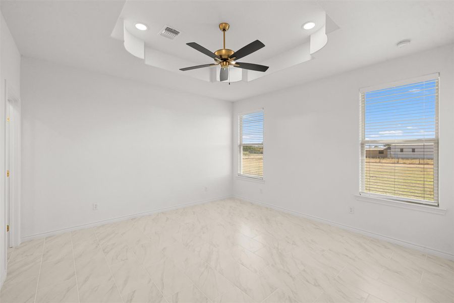 Empty room featuring a ceiling fan, a tray ceiling, and recessed lighting