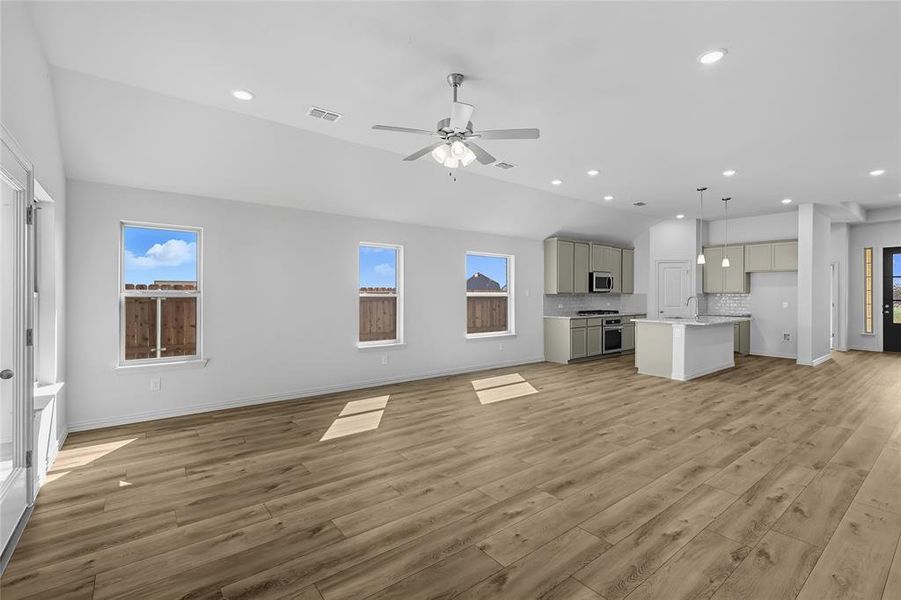 Unfurnished living room with plenty of natural light, recessed lighting, light wood-style floors, ceiling fan, and lofted ceiling Unfurnished living room with plenty of natural light, recessed lighting, light wood-style floors, ceiling fan, and lofted ceiling