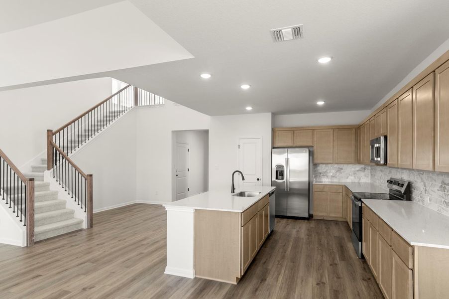 Kitchen with stainless steel appliances, decorative backsplash, dark wood-type flooring, an island with sink, and recessed lighting