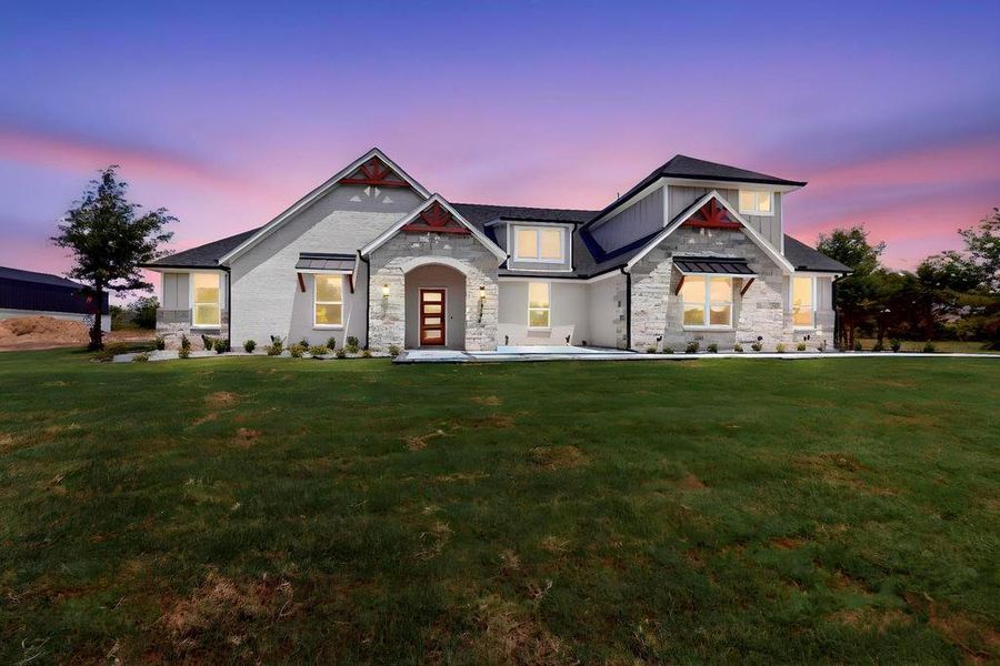 View of front facade with stone siding, a front lawn, and board and batten siding