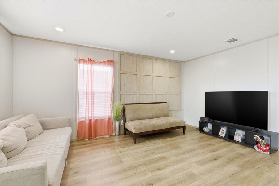 Natural light illuminates the living area, highlighting the warm wood flooring and paneling.