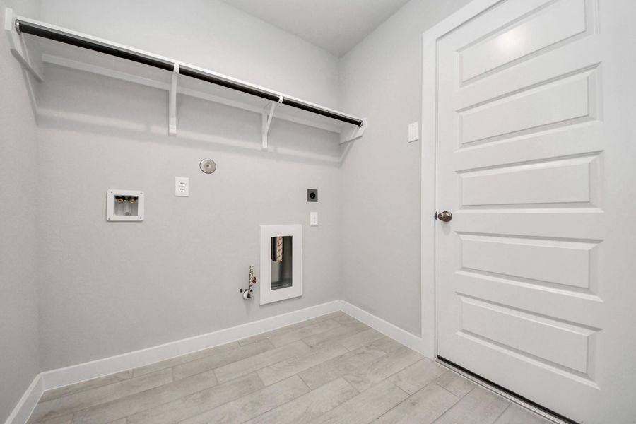 A perfect blend of functionality and comfort. Capture the essence of easy living with a first-floor laundry room, thoughtfully equipped with shelving for effortless organization. Both electric and gas connections available. Sample photo of completed home with similar floor plan. Actual colors and selections may vary.