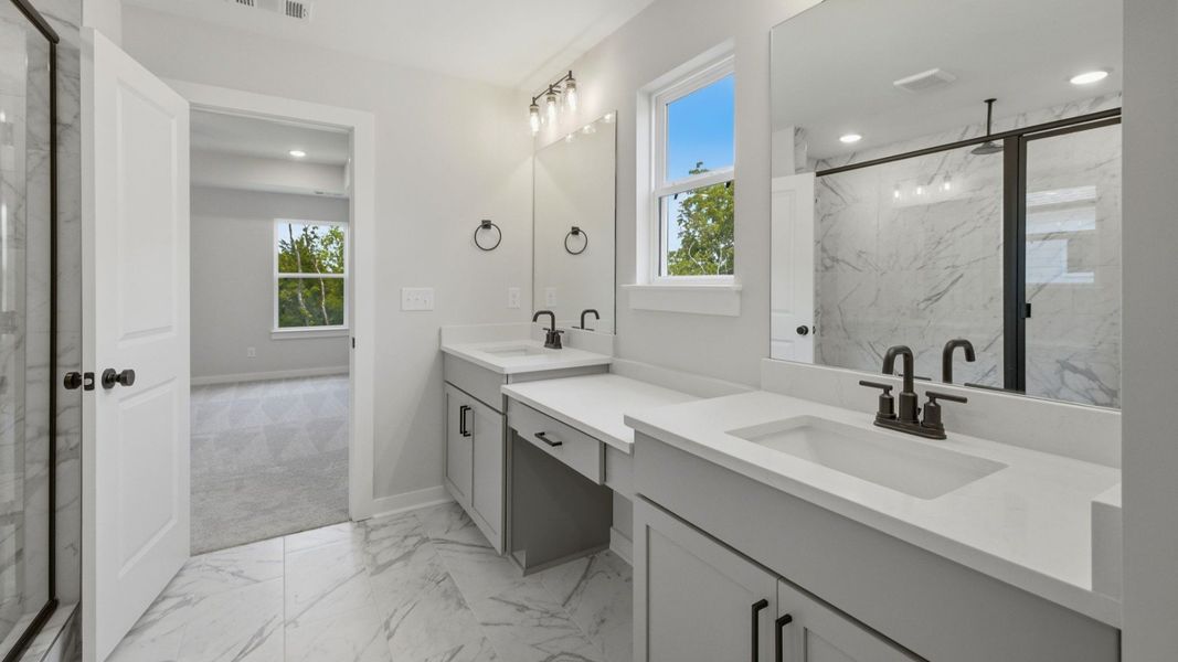 Primary bathroom with dual vanity, glass enclosed shower, and access to suite
