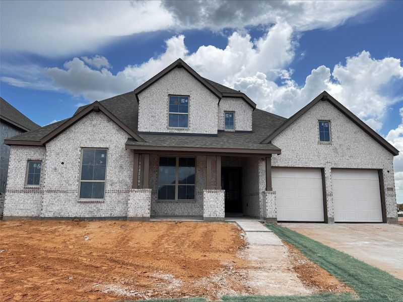 A two-story brick home features dark gabled roofs, a covered front porch, and an attached three-car garage. Elevation C