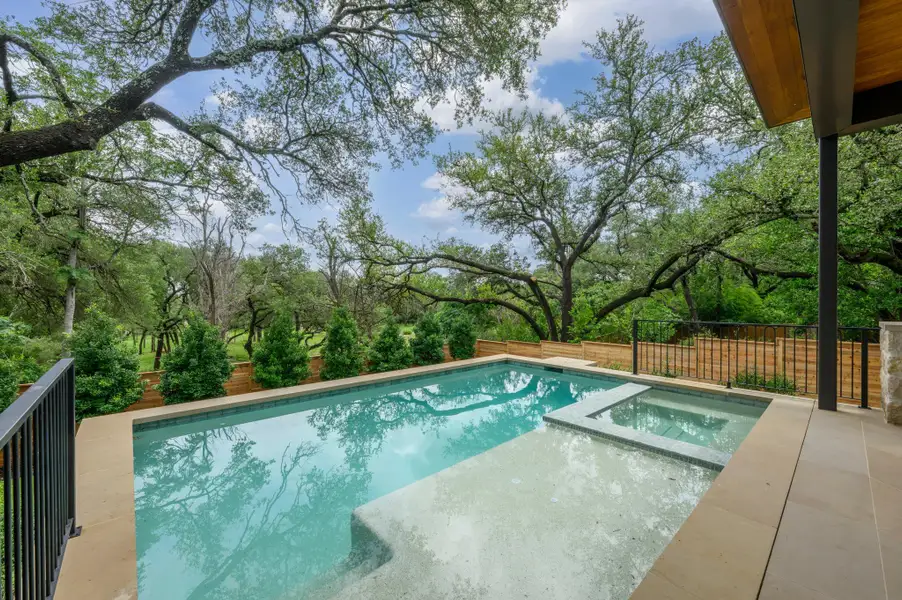 An inviting outdoor pool with integrated spa and lush green surroundings offers a serene escape. An inviting outdoor pool with integrated spa and lush green surroundings offers a serene escape.