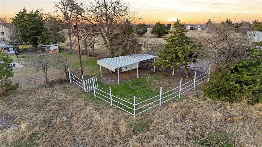 View of yard with an outdoor structure, a carport, and view of wooded area