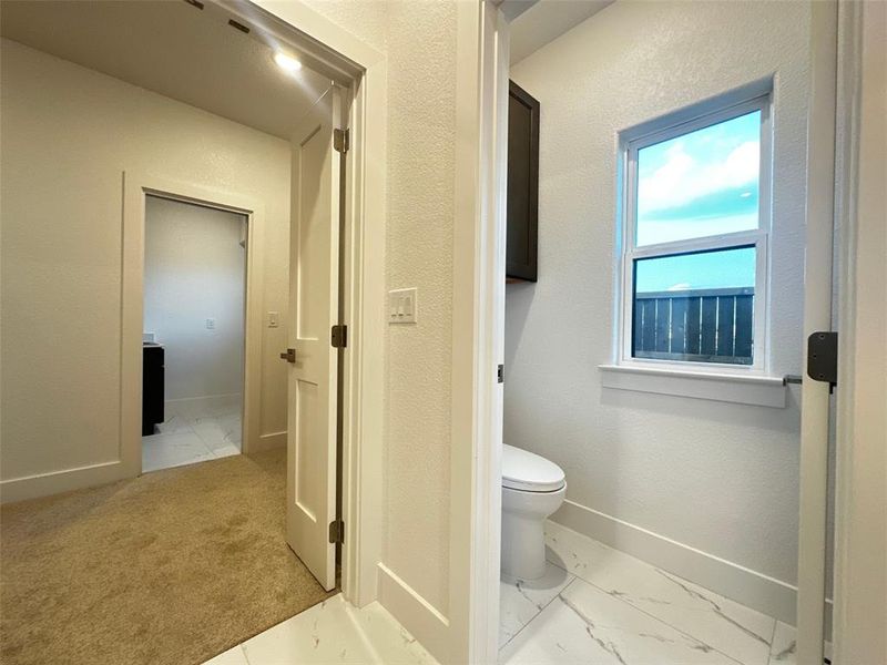 Bathroom with marble finish floor, toilet, and baseboards