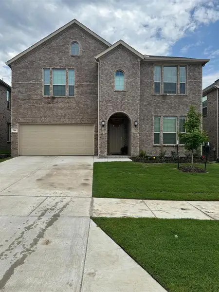 Two-story brick exterior featuring a vaulted entry, arched windows, and an integrated two-car garage Two-story brick exterior featuring a vaulted entry, arched windows, and an integrated two-car garage
