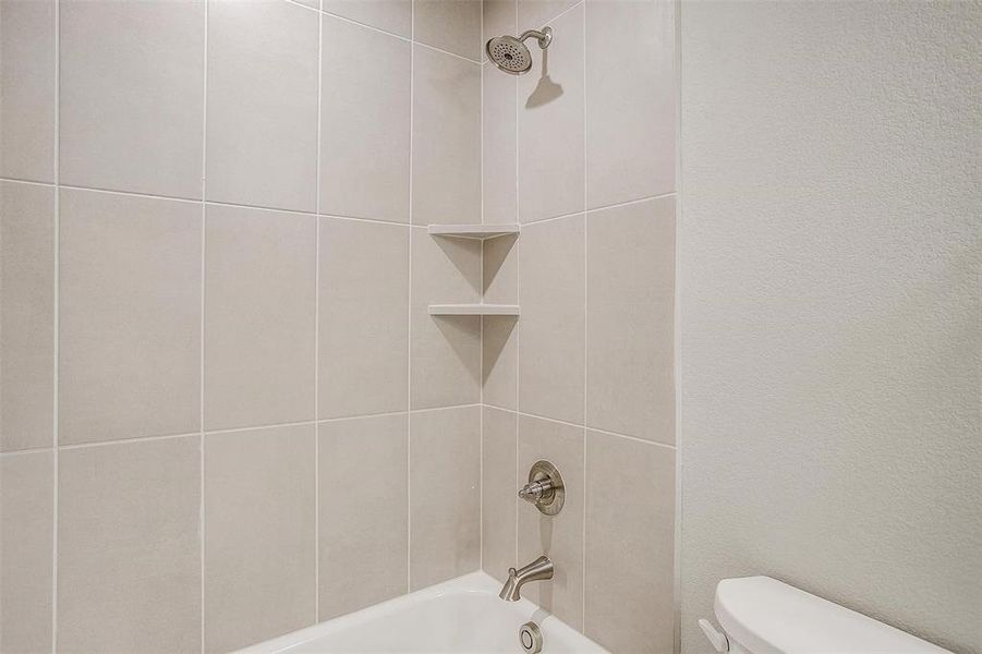 Bathroom featuring tiled shower / bath and toilet