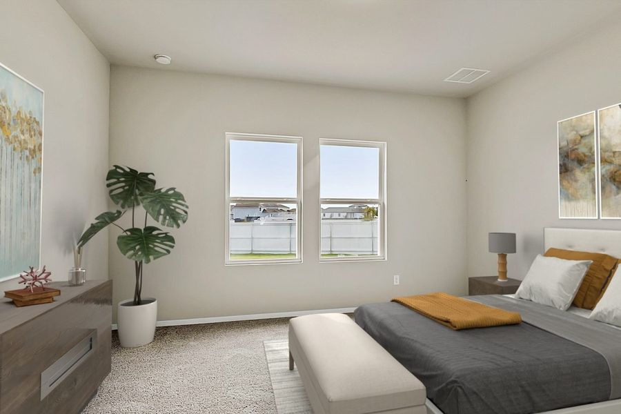 Image of a primary bedroom with a queen bed and bed frame, a large plant in the left corner and a side table with a lamp in the corner