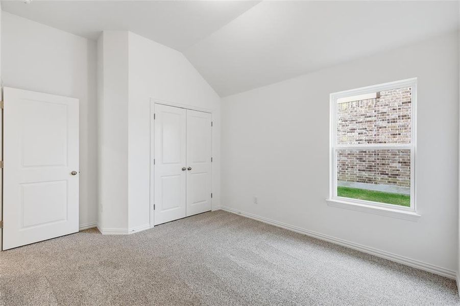 Carpeted interior room featuring a window with exterior brick wall scenery, double bifold closet doors, and an additional white panel door