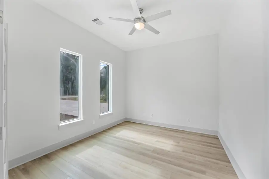 Bright room with two tall windows, light wood flooring, and a ceiling fan. Ideal for a small bedroom or office space. Bright room with two tall windows, light wood flooring, and a ceiling fan. Ideal for a small bedroom or office space.
