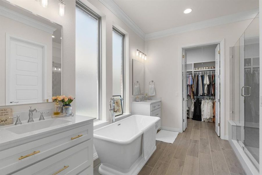 Bathroom with a shower stall, crown molding, two vanities, wood finish floors, and a freestanding tub Bathroom with a shower stall, crown molding, two vanities, wood finish floors, and a freestanding tub