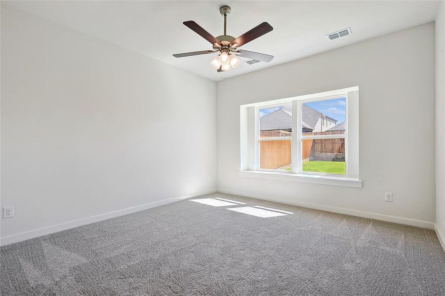 Carpeted empty room featuring ceiling fan