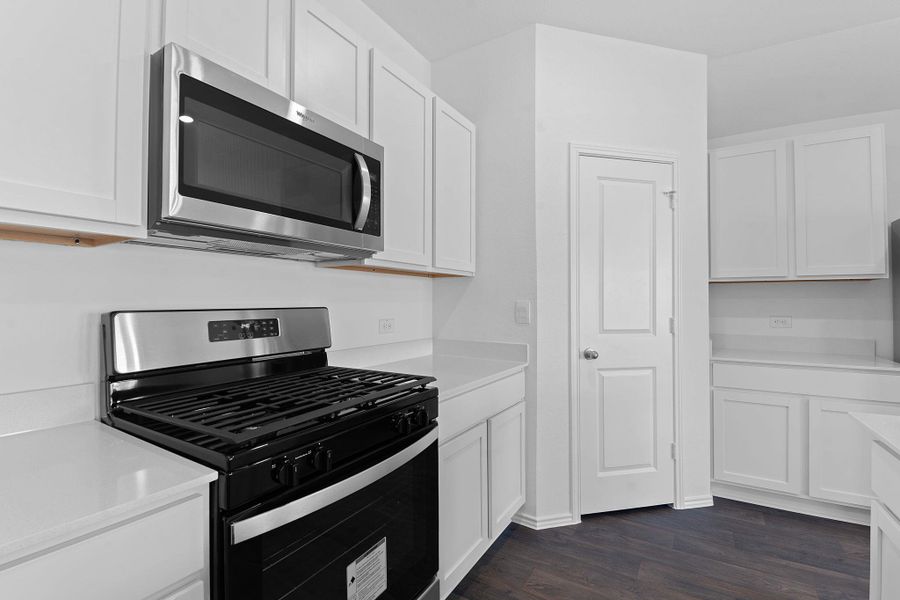 Kitchen with dark wood-style floors, light countertops, appliances with stainless steel finishes, and white cabinetry