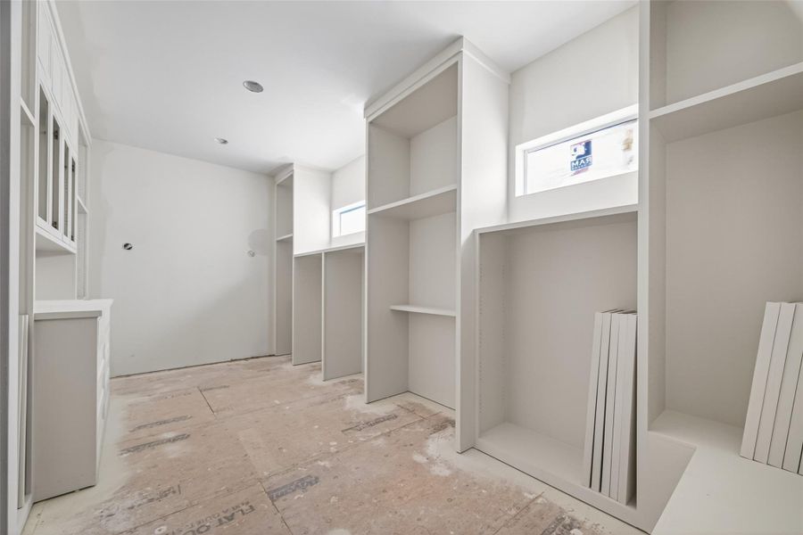 Boutique-style primary closet featuring soaring high ceilings and extensive custom built-in shelving